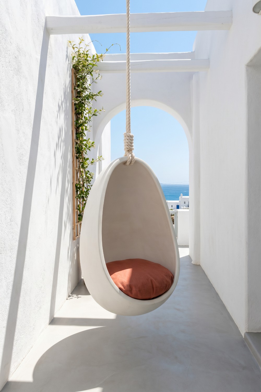 Sculptural white swings in balcony with orange cushion